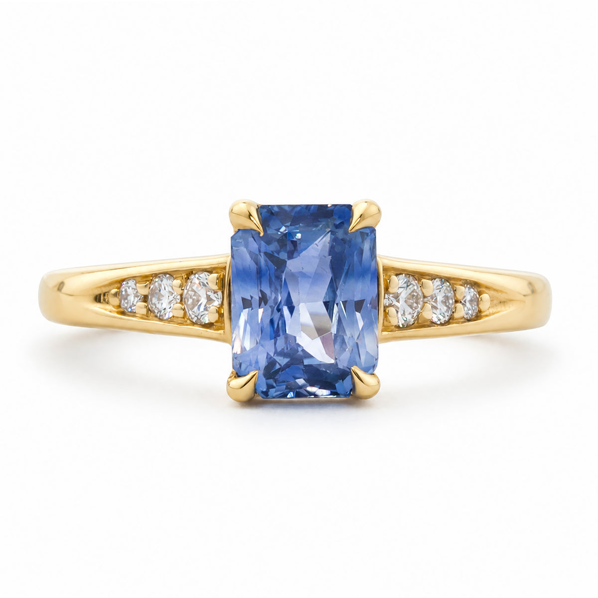A vintage-inspired, blue sapphire and diamond flanked solitaire engagement ring set in 14ct yellow gold. 