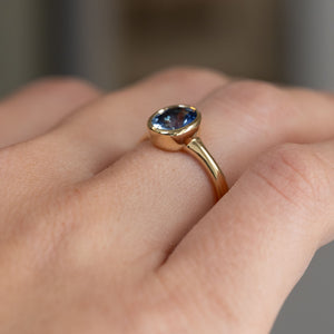 Low three-quarter perspective of the ring being worn, revealing the elevated bezel and tapered shoulders.