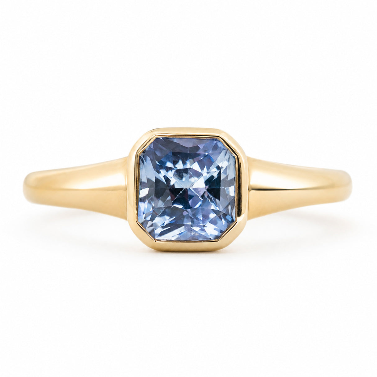 An antique-inspired, pale blue sapphire  set in a rub-over setting in yellow gold.
