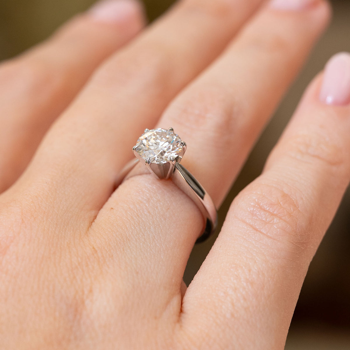 Angled hand view of a vintage white gold solitaire ring, revealing the raised setting and brilliant-cut lab-grown diamond.
