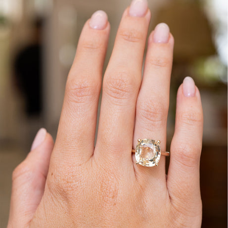An Antique-inspired, Yellow sapphire solitaire engagement ring in yellow gold worn on the hand