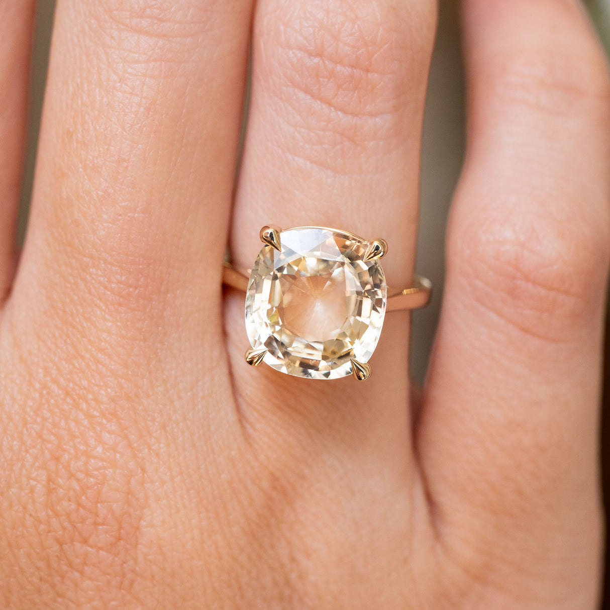 A close-up of a hand wearing an Antique-inspired, Yellow sapphire solitaire engagement ring gold ring 