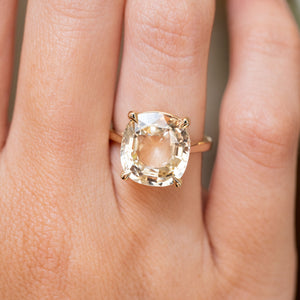 A close-up of a hand wearing an Antique-inspired, Yellow sapphire solitaire engagement ring gold ring 