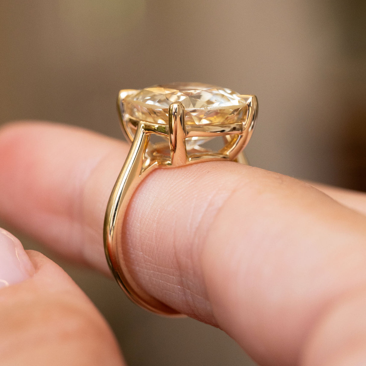 A close-up shot of an Antique-inspired, Yellow sapphire solitaire engagement ring being worn on a finger.