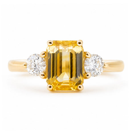An antique-inspired, yellow sapphire and diamond three-stone engagement ring set in yellow gold.