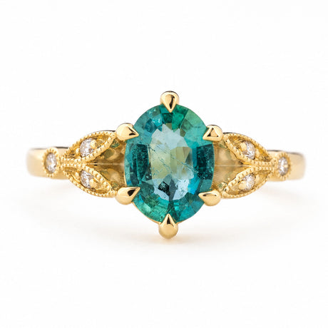 Vintage-inspired, Emerald and diamond engagement ring in yellow gold against a white background