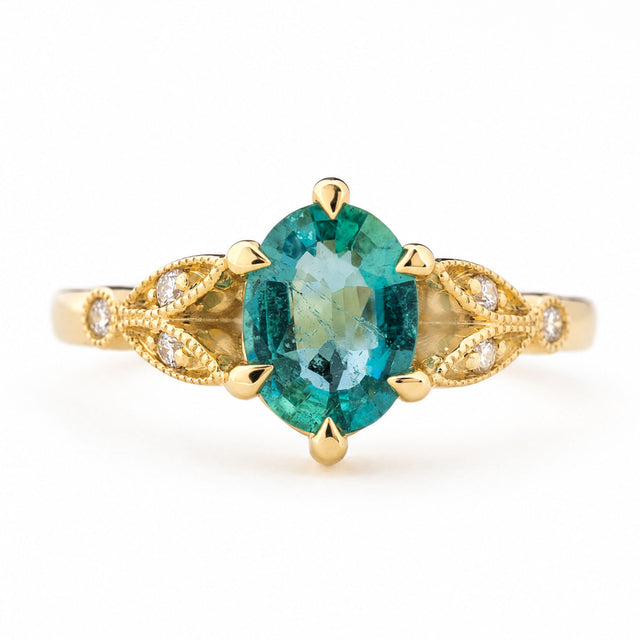 Vintage-inspired, Emerald and diamond engagement ring in yellow gold against a white background