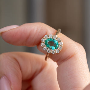 Video presenting the oval emerald and diamond cluster ring balanced on a fingertip for a detailed face-on view.