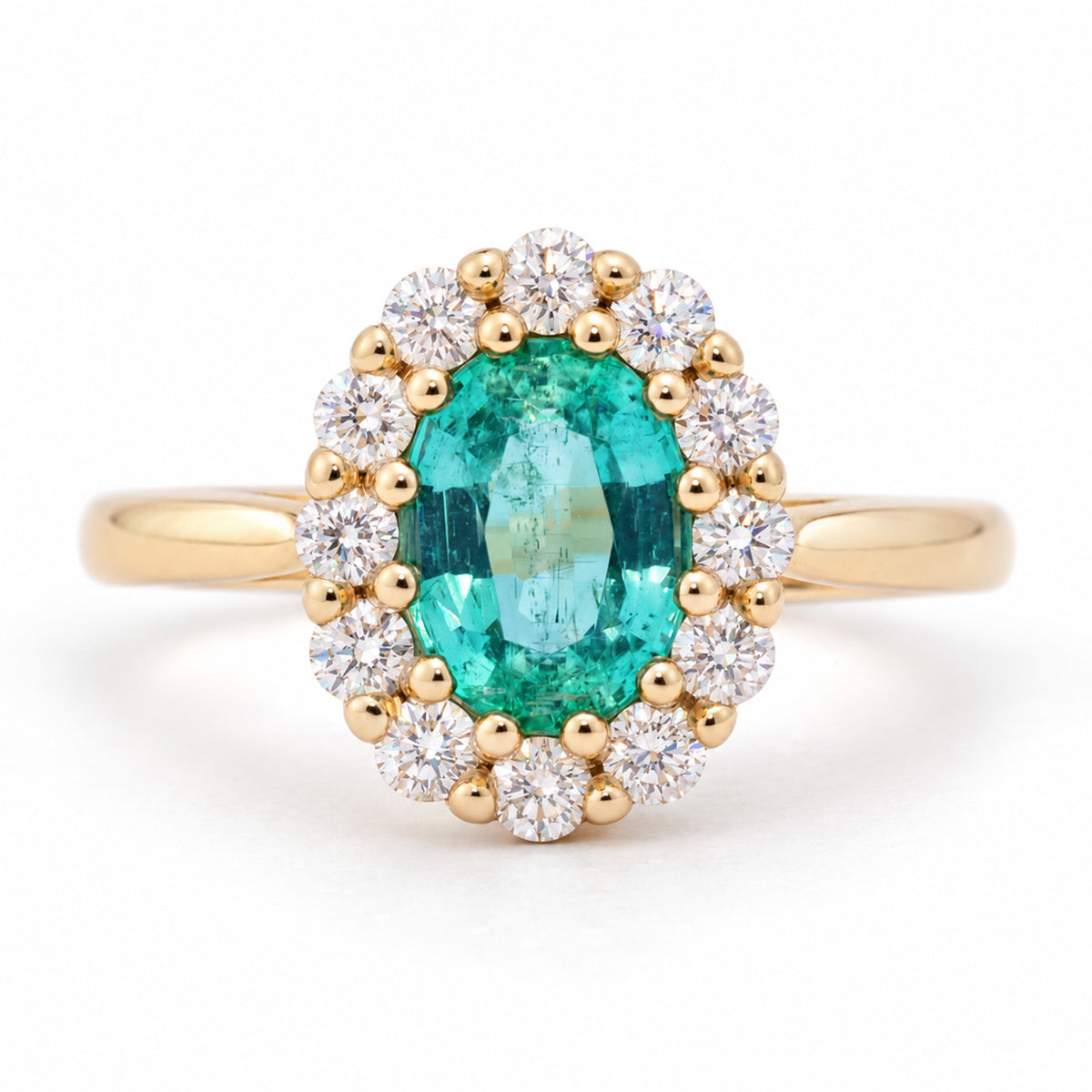 Antique-inspired oval emerald and diamond cluster engagement ring in yellow gold, framed by a halo of round diamonds.