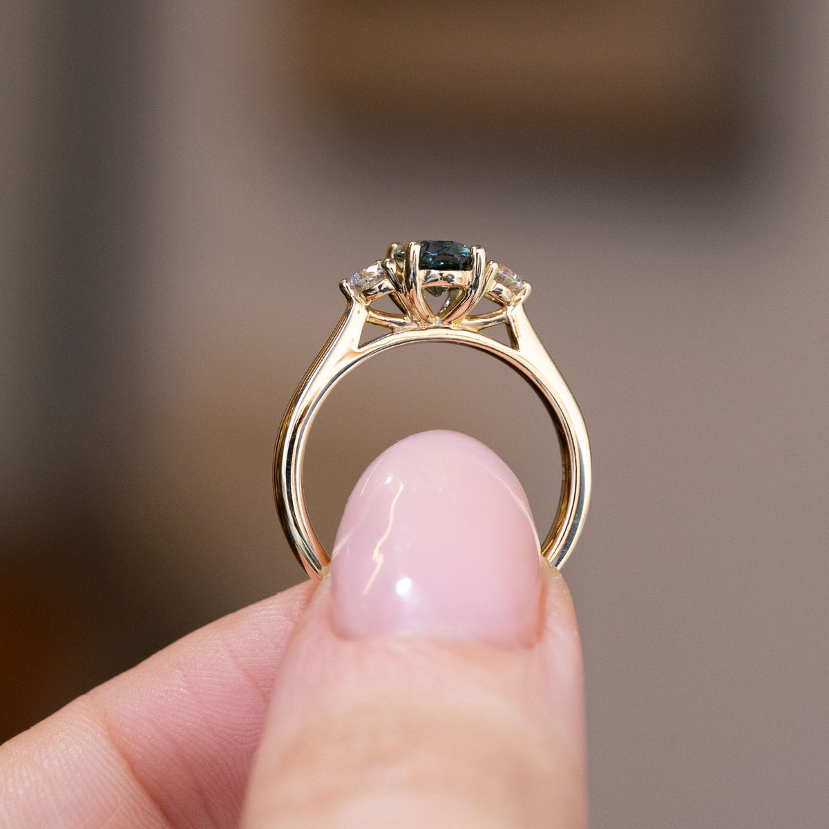 Side profile of the antique-inspired three-stone engagement ring, revealing the open gallery and elegant yellow gold band.