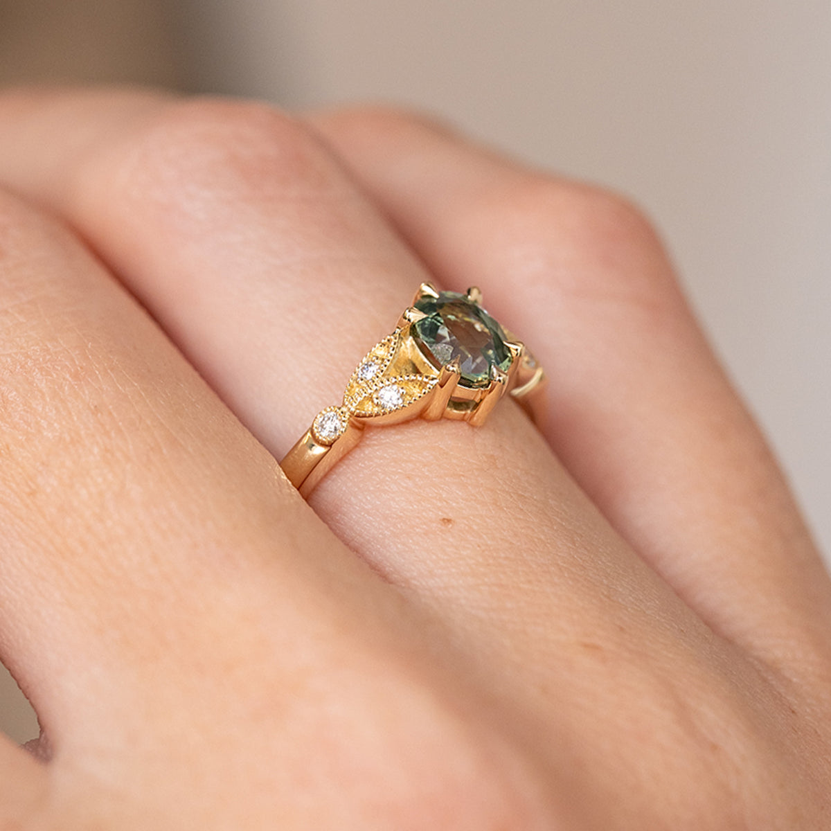 Side angle on the hand revealing the raised sapphire setting, openwork shoulders and fine beaded detailing.