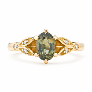 Vintage-inspired, Green sapphire and diamond engagement ring against a plain white background