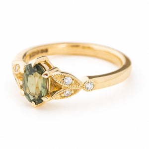 Vintage-inspired, Green sapphire and diamond engagement ring against a white background shown from an angle