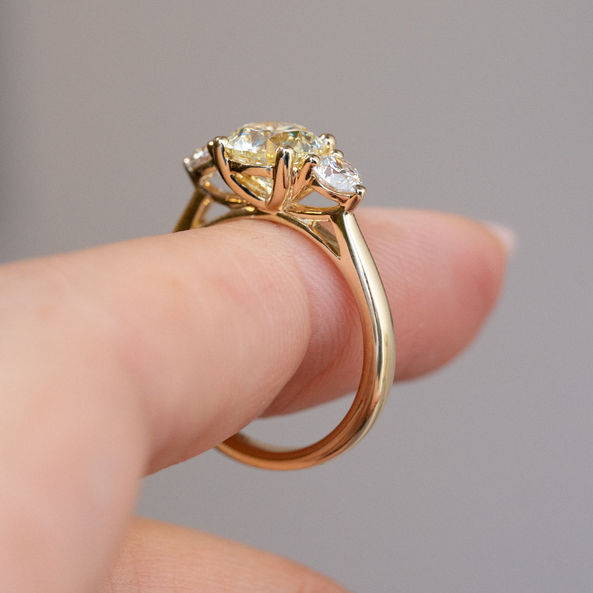 Side profile of the antique-inspired diamond ring, revealing its openwork gallery and polished yellow gold band.