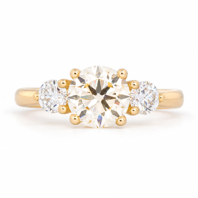 Antique-inspired pale yellow oval diamond three-stone engagement ring in yellow gold, front view.