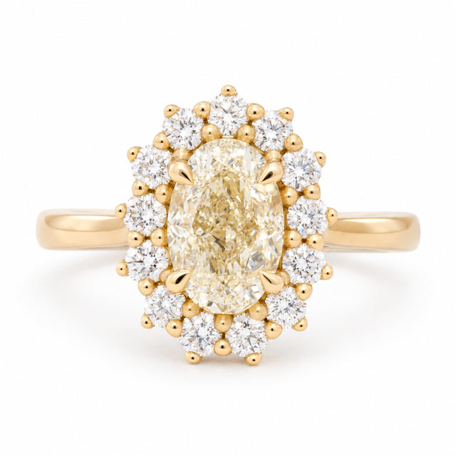 Antique-inspired yellow oval diamond cluster engagement ring surrounded by brilliant-cut white diamonds in yellow gold, front view.