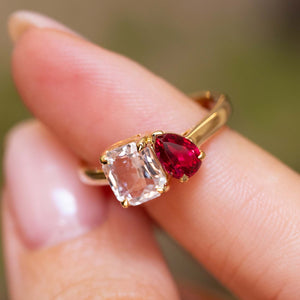 A close-up of a gold Antique-inspired, Pink sapphire and spinel Toi et Moi engagement ring worn on a person's finger.