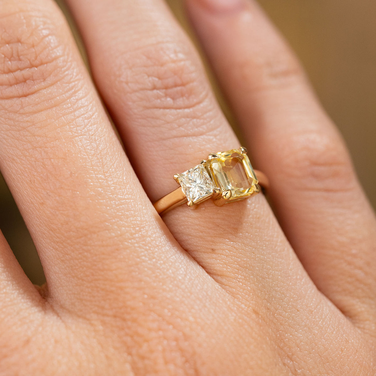 A close-up of a hand wearing a yellow gold Antique-inspired, Diamond and yellow sapphire Toi et Moi engagement ring.