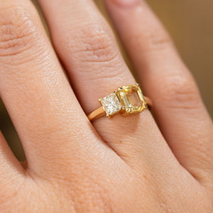 A close-up of a hand wearing a yellow gold Antique-inspired, Diamond and yellow sapphire Toi et Moi engagement ring.