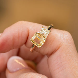 A close-up of a hand wearing a yellow gold Antique-inspired, Diamond and yellow sapphire Toi et Moi engagement ring