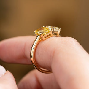 A close-up of an Antique-inspired, Diamond and yellow sapphire Toi et Moi engagement ring in yellow gold worn on a finger and shown from the side to display the profile and shank