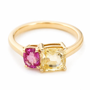 an Antique-inspired, Yellow and pink sapphire two stone yellow gold ring against a plain white background shown from an above angle.