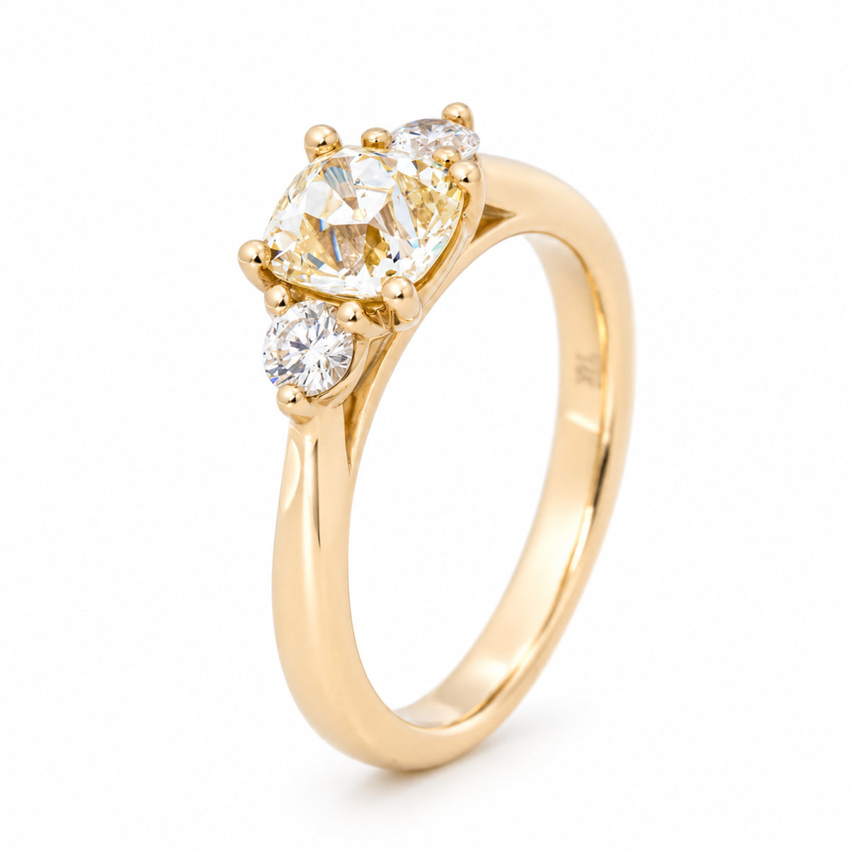 Angled view of the cushion-cut diamond ring, highlighting the raised claw setting and polished yellow gold band.