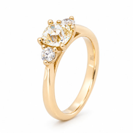 Angled view of the cushion-cut diamond ring, highlighting the raised claw setting and polished yellow gold band.