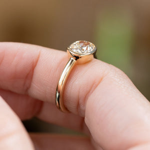 Profile view of an antique-style old-mine cut diamond solitaire ring, highlighting the elevated rub-over setting and polished yellow gold band.