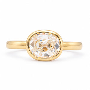 Front view of an antique-inspired elongated cushion old-mine cut diamond solitaire engagement ring in a polished 14ct yellow gold rub-over setting.