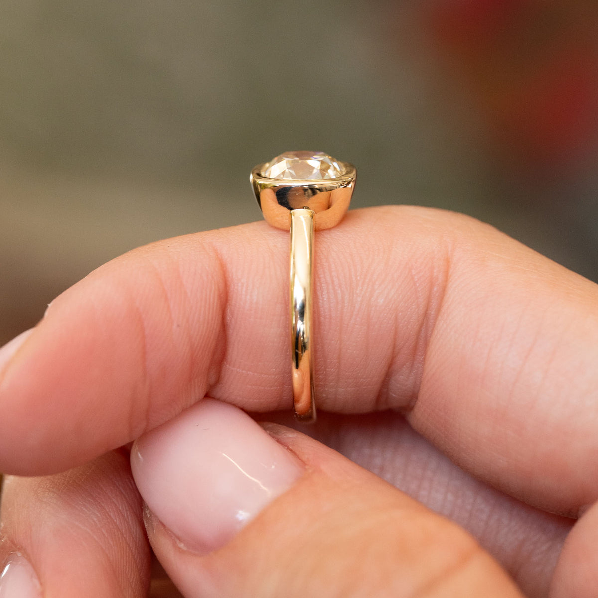 Profile view of an antique-inspired cushion old-mine cut diamond solitaire, showing its substantial yellow gold setting and slim shank.