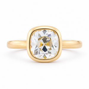 Front view of an antique-inspired yellow-tinted cushion old-mine cut diamond solitaire engagement ring in polished yellow gold.