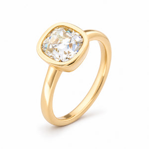 Angled product view of an antique-inspired engagement ring featuring a cushion old-mine cut diamond in a smooth yellow gold rub-over setting.