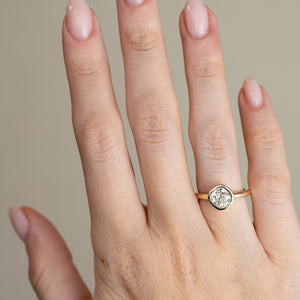 A yellow gold diamond solitaire worn on a hand, highlighting the understated design and distinctive antique-style diamond cut.