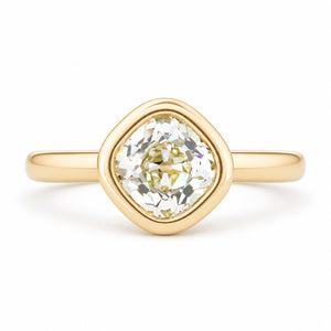 An antique-inspired solitaire engagement ring featuring an old mine-cut diamond in a rounded yellow gold bezel setting.