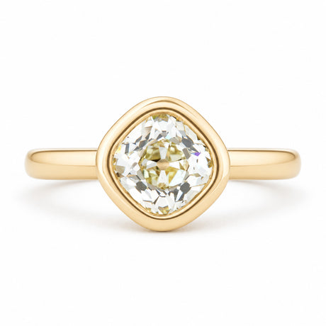 An antique-inspired solitaire engagement ring featuring an old mine-cut diamond in a rounded yellow gold bezel setting.