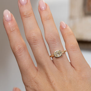Diamond solitaire engagement ring worn on a hand, showcasing its delicate proportions and warm champagne tones.