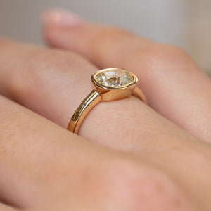 Side-angle view of the bezel-set diamond ring worn on a hand, highlighting the raised setting and polished yellow gold band.