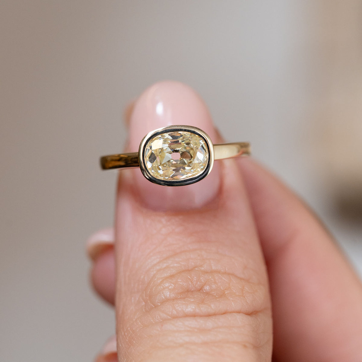 Hand-held close-up of the old mine-cut diamond, showcasing its antique-style faceting and elegant bezel setting.