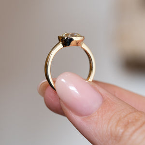 Side profile of the yellow gold solitaire engagement ring, revealing the raised bezel setting and gently tapered band.