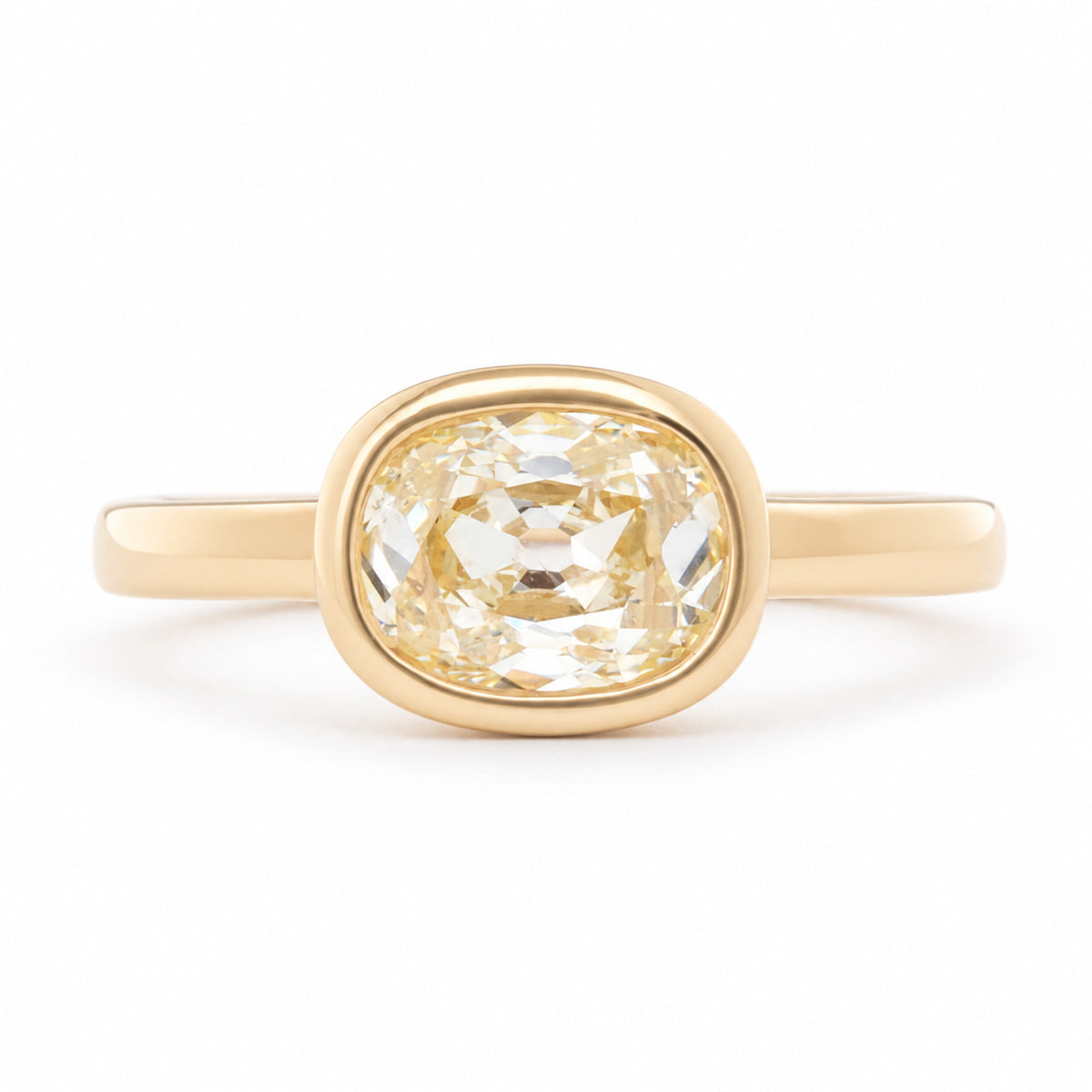 Antique-inspired old mine-cut diamond solitaire engagement ring in yellow gold, featuring a pale champagne diamond in a polished bezel setting.