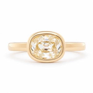 Antique-inspired old mine-cut diamond solitaire engagement ring in yellow gold, featuring a pale champagne diamond in a polished bezel setting.