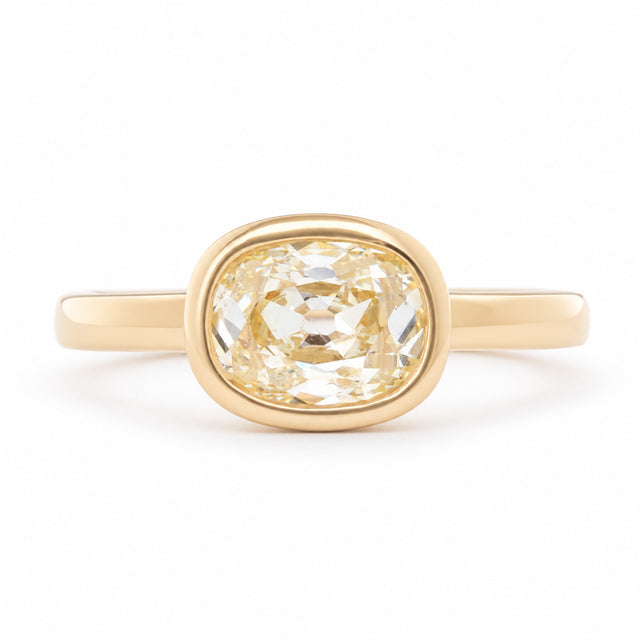 Antique-inspired old mine-cut diamond solitaire engagement ring in yellow gold, featuring a pale champagne diamond in a polished bezel setting.