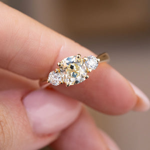 Handheld close-up of the antique-inspired diamond trio in yellow gold.