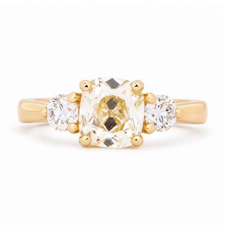Antique-inspired old-mine diamond three-stone engagement ring in yellow gold.