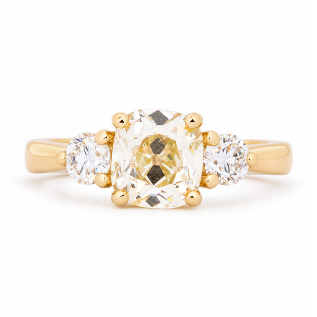 Antique-inspired old-mine diamond three-stone engagement ring in yellow gold.