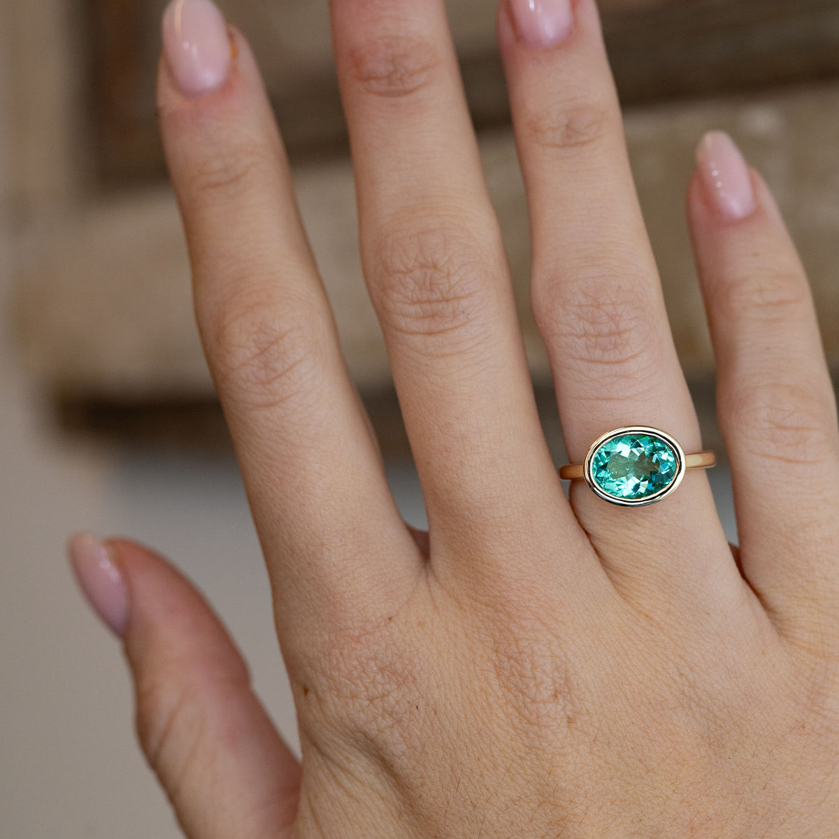 Sea-green beryl solitaire engagement ring worn on a hand, showcasing its vibrant turquoise-green colour and minimalist design.