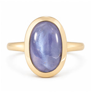 Antique-inspired cat's eye sapphire solitaire engagement ring in yellow gold, featuring an oval blue-purple cabochon gemstone in a smooth bezel setting.