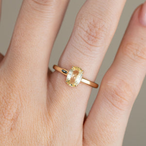 Close-up of the antique-inspired yellow gold ring on a finger, showing the elongated oval sapphire and refined claw setting.