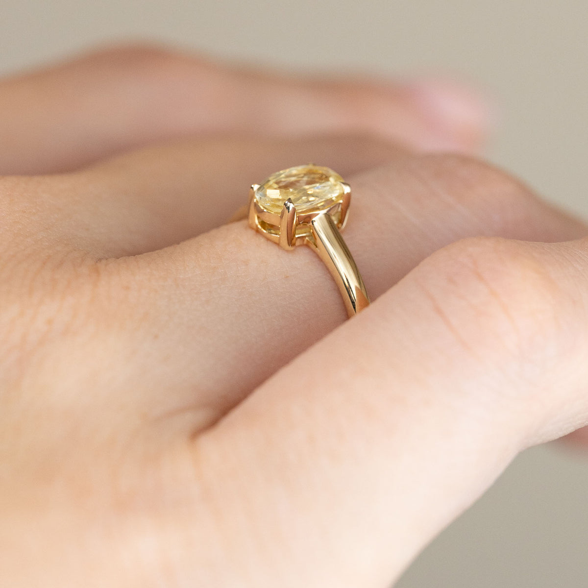 Side-angle view of the yellow sapphire engagement ring worn on a hand, displaying its elevated gemstone setting and graceful gold shoulders.